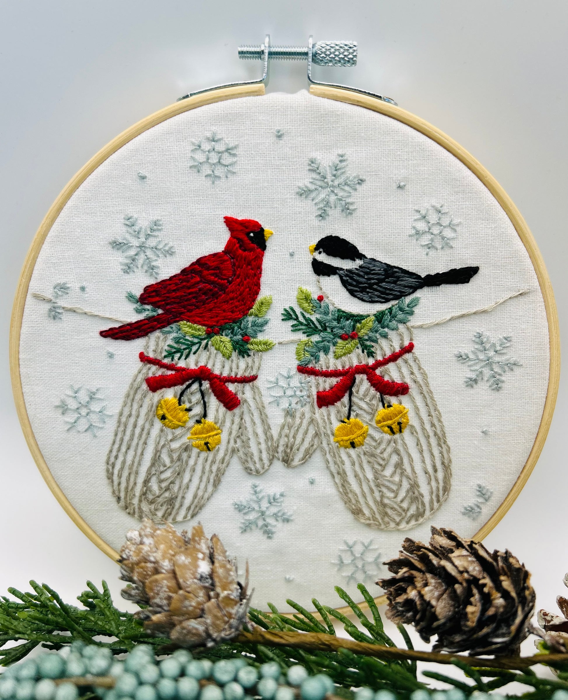 Embroidery hoop with winter-themed design featuring mittens, birds, and snowflakes. Coordinates with "When Snow  Falls" fabric by Deb Strain.