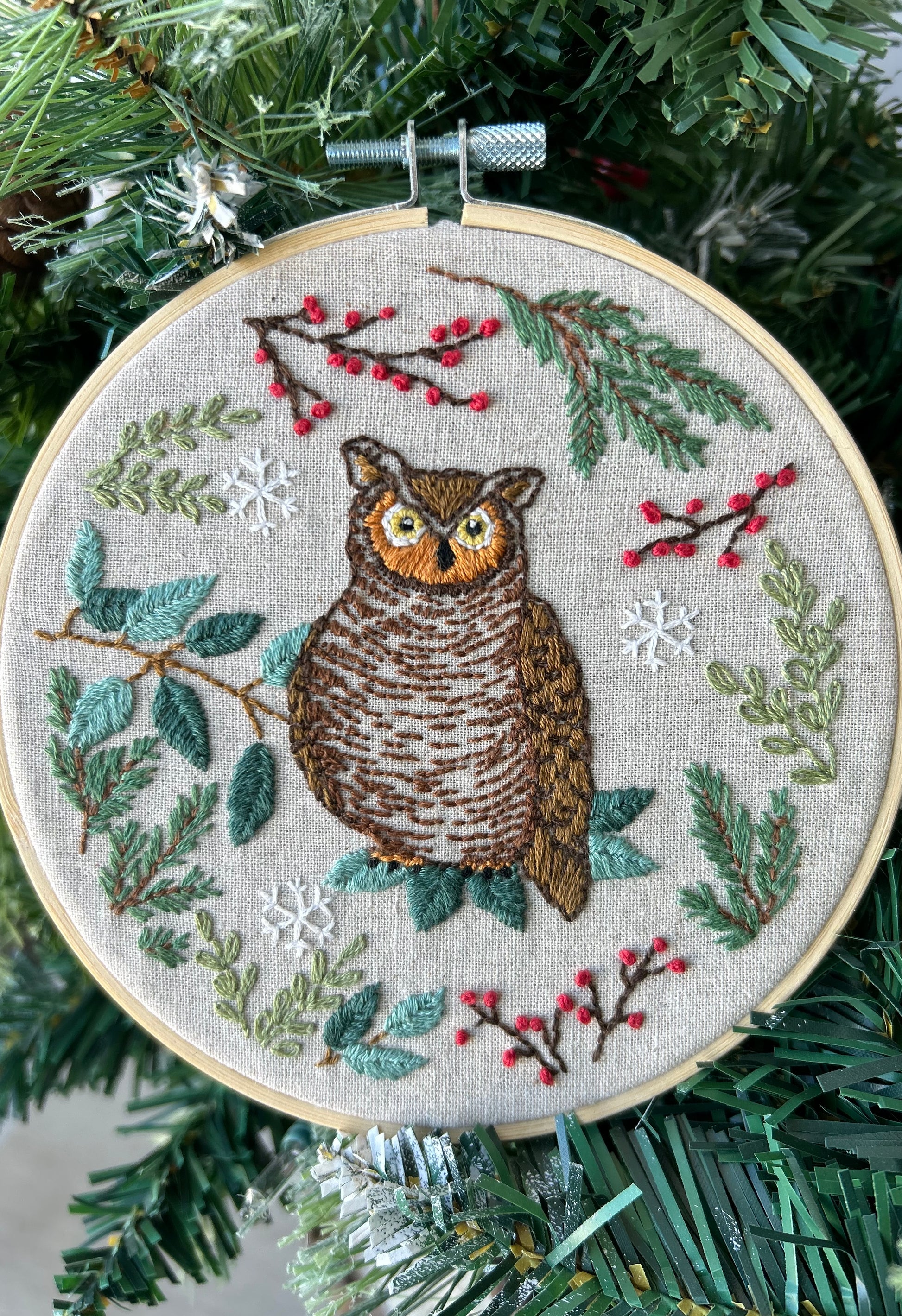 An embroidery kit depicting an owl surrounded by foliage and berries, displayed in a 6-inch hoop designed by Deb Strain.